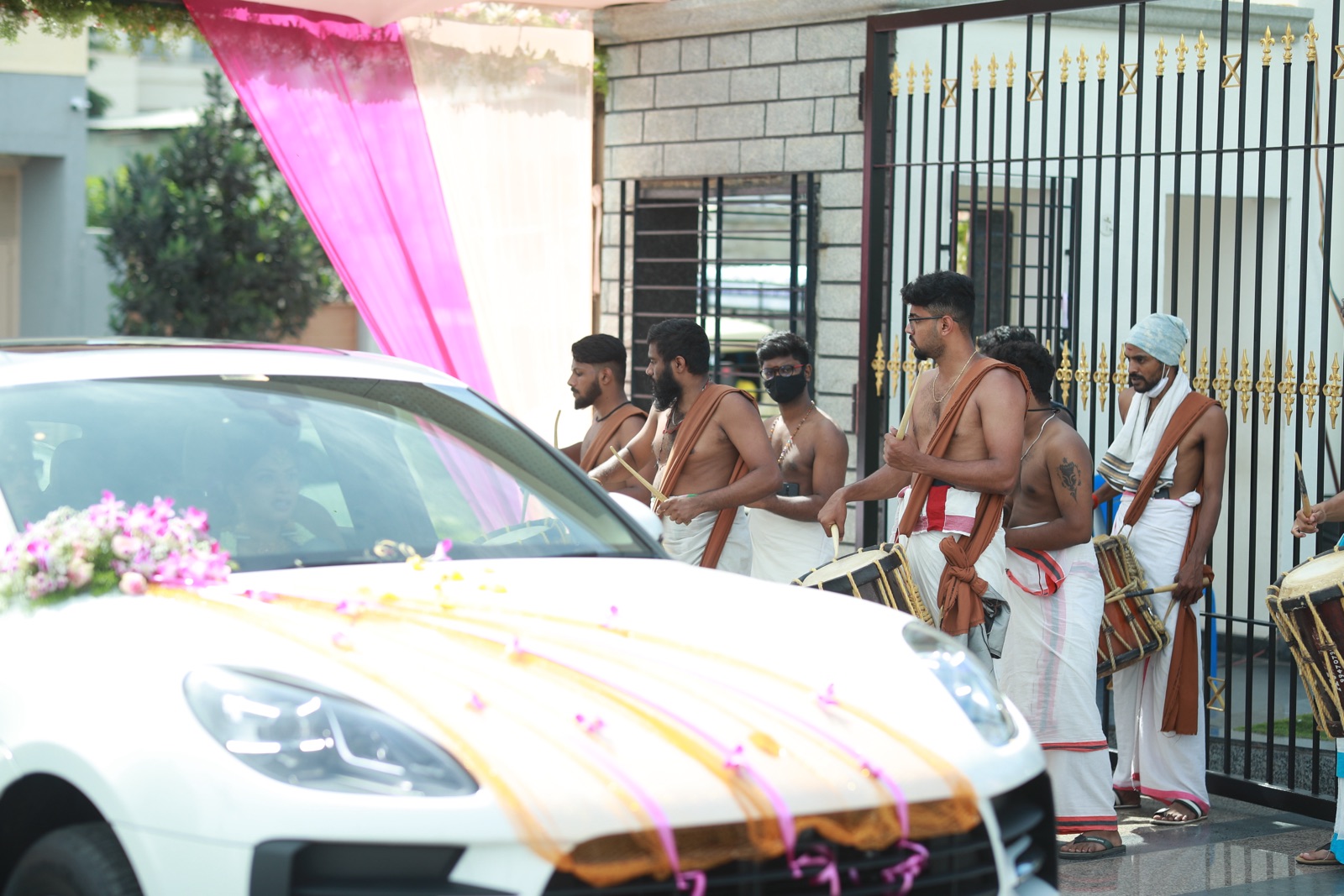 Traditional drummers welcoming a decorated wedding car at the gate